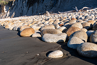 coastal boulder field with black sand beach and cliffs West Coast New Zealand geology