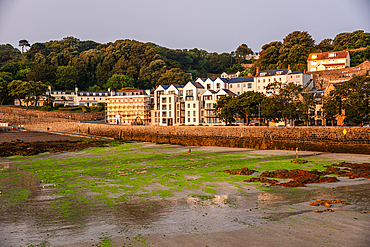 Scenic St Peter Port Guernsey harbourfront with hillside houses tidal flats and tranquil maritime character at sunset on the Channel Islands