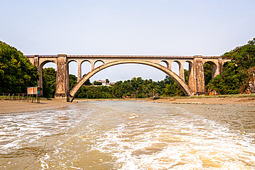 Perspective view of the Viaduc de Lessard railway viaduct above sandy banks of the Rance estuary in Brittany, France.