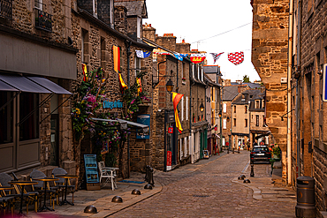 Medieval cobblestone street Rue du Jerzual with shops and flags in historic town of Dinan Brittany France