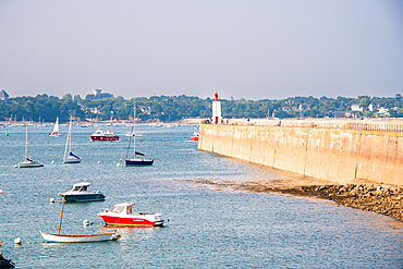Boats anchored by the lighthouse at the entrance of Saint-Malo harbor, Brittany France. Môle des Noires