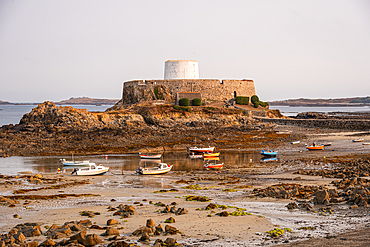 Fort Grey Martello tower on rocky islet with boats at low tide in Guernsey Channel Islands