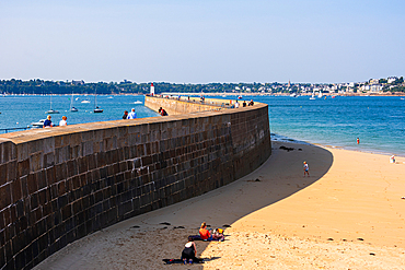 Golden sandy beach curving along stone seawall in Saint-Malo Brittany France coastal view