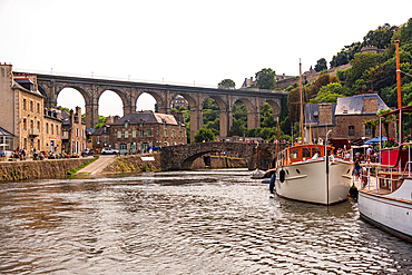 River Rance with boats sailing under Dinan viaduct and old stone bridge Brittany France