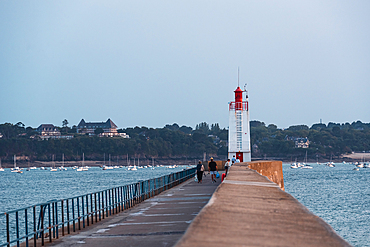 A long stone pier stretches into the English Channel ending at the Saint-Malo lighthouse, a guiding beacon for vessels entering the historic port.