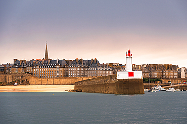 Lighthouse and stone jetty at the entrance of Saint Malo harbor with view of fortified old town Brittany France