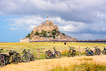 View of Mont Saint-Michel with rows of bicycles parked along the access path to the tidal island.