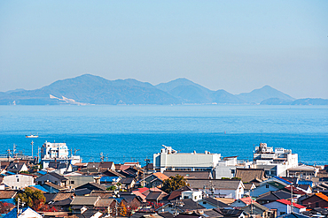 Coastal city roof tops, a calm blue sea and islands on the horizon, Tomonoura, Honshu, Japan, Asia