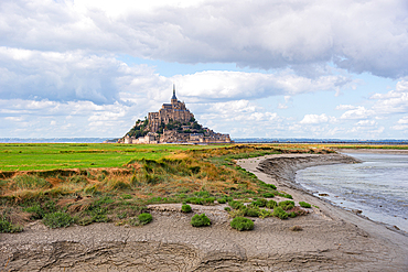 View of Mont Saint-Michel across the tidal marshes, known for grazing salt-meadow sheep, Normandy, France.