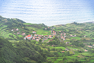 Scenic view of Fajãzinha, a small coastal village surrounded by the Atlantic Ocean and steep green cliffs, Flores Island, Azores, Portugal.
