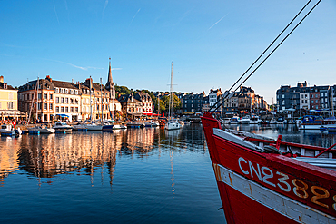 Panoramic view of the Vieux Bassin, Honfleur’s historic harbor, with reflections of boats and medieval buildings on the calm water.