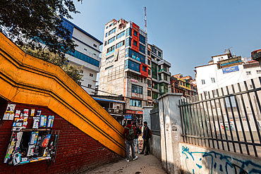 Yellow pedestrian bridge and fences leading the eye to an intricate building on New Road, Kathmandu, Nepal, Asia