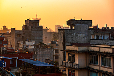 Hazy orange sunrise above residential roofs in Kathmandu Thamel, Kathmandu, Nepal, Asia