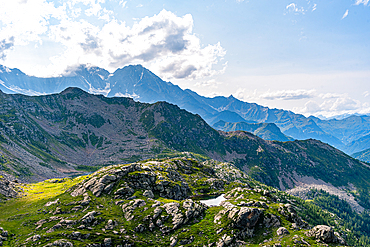 Mountain meadow with a lake on a high plateau and view over high mountains with towering summits of the Swiss Alps on the horizon, Switzerland, Europe