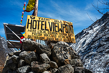 Yellow Hotel Sign on rocks in front of mountain slopes, Langtang Valley trek, Himalayas, Nepal, Asia