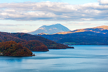 View over the forest slope of Lake Toya in the evening with volcano in the distance, Abuta, Hokkaido, Japan, Asia