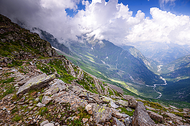 Beautiful hiking path on steep rocky and grassy slopes in the Alps of Italy. Colle del Turlo. Dramatic mountain landscape overlooking a vast valley