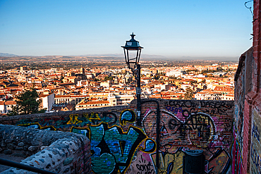 Walls and lantern in front of the skyline of Granada at sunrise. Albaicin, Granada, Andalucia, Spain