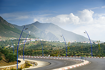 Scenic curvy road with blue lanterns leading to the Riff mountains and city of Chefchaouen in Morocco