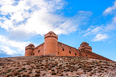 Castillo de La Calahorra, Guadix, Spain. red castle walls against a blue sky