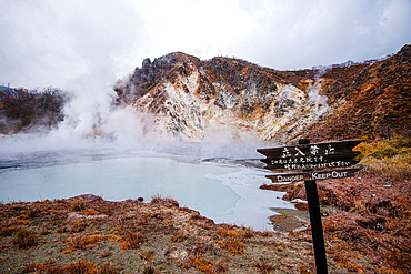 Danger sign in front of volcanic field and steaming pond in Noboribetsu, Hell Valley, Hokkaido, Japan, Asia