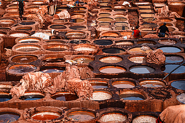 Rows of dye-filled stone basins in a traditional leather tannery in Fes, Morocco, showcasing intricate tanning methods and craftsmanship.