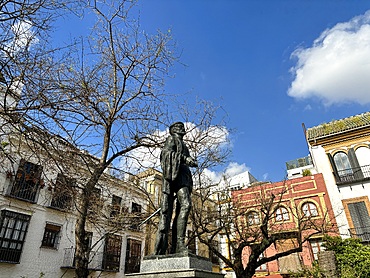 View of the Plaza de los Refinadores monument in Seville, featuring a life-size bronze sculpture of Don Juan Tenorio, a fictional character from Spanish literature. The sculpture depicts Don Juan adorned in typical 17th-century attire.