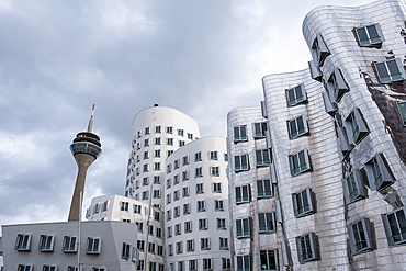 View of the Neuer Zollhof (The New Zollhof), named after a former customs facility, a prominent landmark of Dusseldorf-Hafen, part of the redeveloped port of Dsseldorf,  with the Rheinturm (Rhine Tower) telecommunications tower in the background, Dusseldorf, North Rhine Westphalia, Germany, Europe