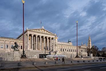 Vienna, Austria – View of the Austrian Parliament's grand neo-Greek entrance facade on Ringstrasse, featuring the monumental Pallas Athena fountain and sculpted ramp of the Theophil Hansen-designed building.