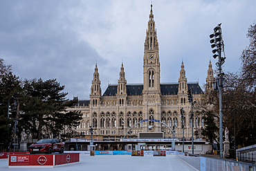 Vienna, Austria – Winter view of Rathausplatz with the festive ice skating park in foreground, the neo-Gothic City Hall facade illuminated against the cold evening sky.