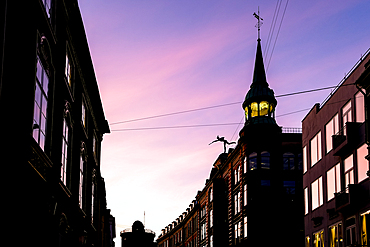 Copenhagen, Denmark – Architectural detail of the Mercury statue atop Købmagergade 52, sculpted by Julius Schultz in 1896. Far in the background, the historic Rundetårn observatory.