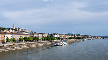 Budapest, Hungary – View from the Pest bank of the Danube River with Matthias Church and Fisherman's Bastion rising on the Buda side, framing the city’s historic skyline across the water.