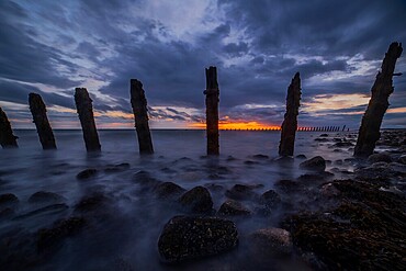 Storm clouds gather over the Irish Sea, worn sea defences from South Walney at sunset from the Cumbrian Coast, Cumbria, England, United Kingdom, Europe