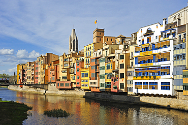 front of the houses, among which the white Casa Maso, birthplace of the Catalan architect Rafael Masó (1880-1935), by the Onyar River, with the tower bell of Collegiate Church of San Felix in the background, Girona, Catalonia, Spain,Europe