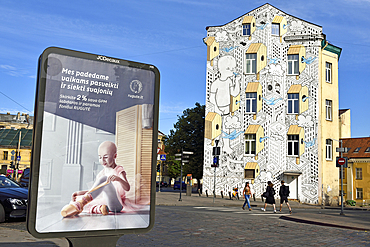 Billboard with poster calling for a donation for RUGUTE childhood cancer fund, in front of a mural painting by the Italian artist Millo, on the building opposite Hales Market, Pylimo Street 56, Vilnius, Lithuania, Europe