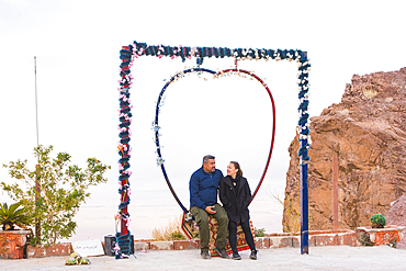 Couple sitting on a heart-shaped swing, Jordan, Middle East