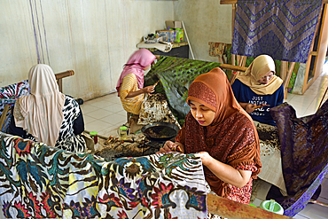 women using a pen-like tool, called 'canting', to apply liquid hot wax in the batik-making process, Wirakuto batik workshop, Pekalongan, Java island, Indonesia, Southeast Asia