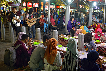 open-air street side restaurant (called lesehan) by night on Malioboro Street, major shopping street in Yogyakarta, Java island, Indonesia, Southeast Asia