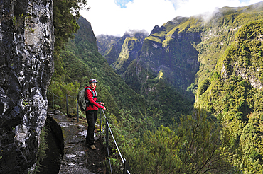 hiker on the path along the levada (aqueduct) of Green Cauldron (Caldeirao Verde),Madeira island,Atlantic Ocean,Portugal