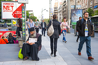 Orthodox priest taking collection at Piata Romana underground station, General Gheorghe Magheru Boulevard, Bucharest, Romania