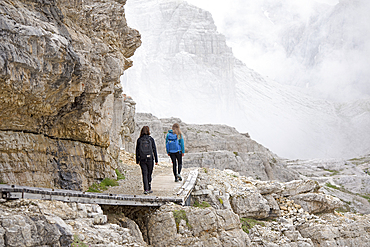 Hikers on path between Locatelli and Pian di Cengia refuges with Punta dei Tre Scarperi behind, Three Peaks Nature Park, Dolomites, South Tyrol, Italy