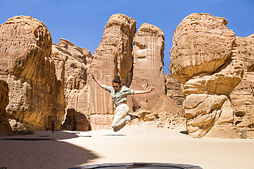 Woman jumping on a trampoline (puddle), installation by artist Manal Aldowayan, entitled 'Now you see Me, Now You Don’t' as part of the 2020 Desert X AlUla exhibition, which took place in the Ashar Valley, Medina Province, Saudi Arabia, Middle East, Medin