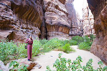 Woman walking at the bottom of a canyon with sandstone walls in the Sharaan Nature Reserve, AlUla, Medina Province, Saudi Arabia, Middle East