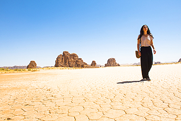 Woman walking on a large dry salt lake in the Sharaan Nature Reserve, AlUla, Medina Province, Saudi Arabia, Middle East