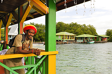 Man leaning on the guardrail of a house on stilts at Cayo Coral, southern headland of Bastimentos Island, Bocas del Toro Archipelago, Republic of Panama, Central America