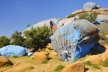 Painter working on Painting Rocks site, work of the Belgian artist Jean Verame. around Tafraout,Anti-Atlas,Morocco,North Africa