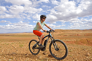 Rider on mountain bike with electric assistance on a track between Ouarzazate and Ait Ben Haddou, Ounila River valley, Ouarzazate Province, region of Draa-Tafilalet, Morocco, North West Africa