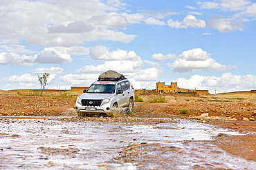 Four-wheel drive vehicle crossing a river with ford on a track between Ouarzazate and Ait Ben Haddou,, Ounila River valley, Ouarzazate Province, region of Draa-Tafilalet, Morocco, North West Africa