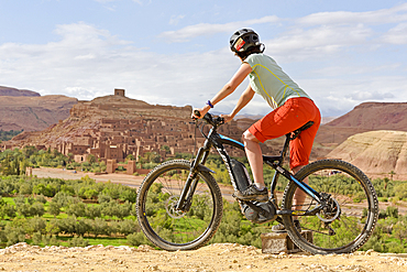 Cyclist on a promontory facing the Ksar of Ait-Ben-Haddou, Ounila River valley, Ouarzazate Province, region of Draa-Tafilalet, Morocco, North West Africa