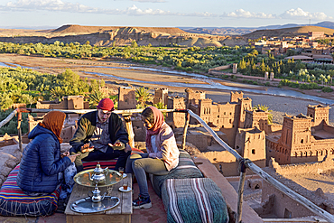 People sitting on the terrace of a cafe overlooking the Ksar of Ait-Ben-Haddou, Ounila River valley, Ouarzazate Province, region of Draa-Tafilalet, Morocco, North West Africa